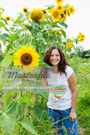 Portrait of young woman with yellow sunflowers in allotment