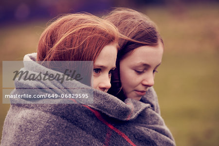 Girls wrapped in a blanket outdoors