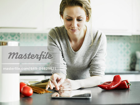 Mid adult woman using digital tablet on kitchen counter