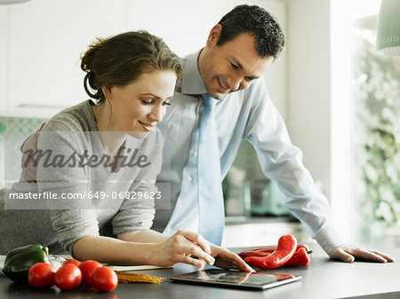 Businessman and wife using digital tablet in kitchen