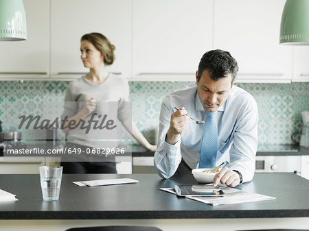 Mature businessman using tablet over breakfast in kitchen