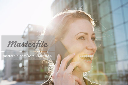 Mid adult woman using cellphone in sunlight outdoors