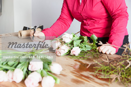 Close up of young woman arranging roses in florists