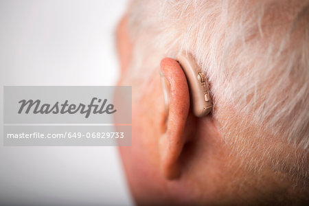 Senior man wearing hearing aid, close up