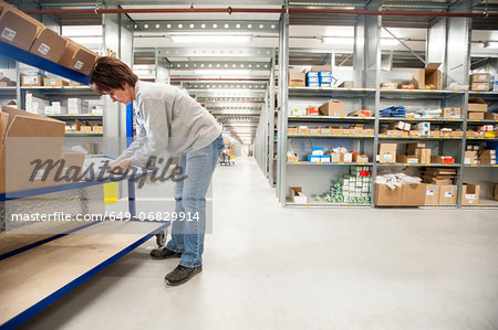 Female warehouse worker checking orders on delivery trolley