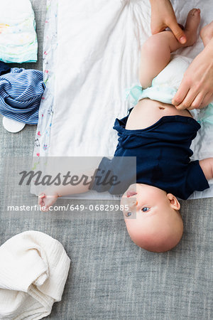 Person changing baby boy's nappy, overhead view