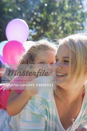 Mother with daughter lying on top in garden