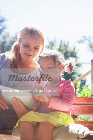 Mother and daughter using laptop in garden