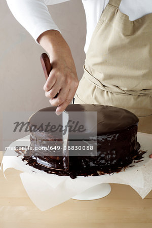 Woman spreading melted chocolate on cake