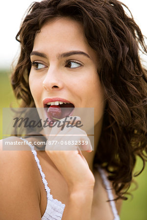 Young woman eating a cherry, oudoors