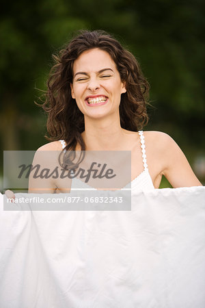 Young woman smiling, in front of a white sheet, oudoors