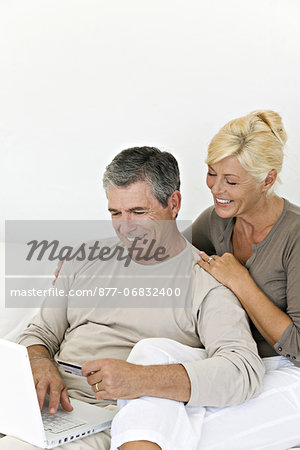 Mature couple using laptop, woman holding a credit card