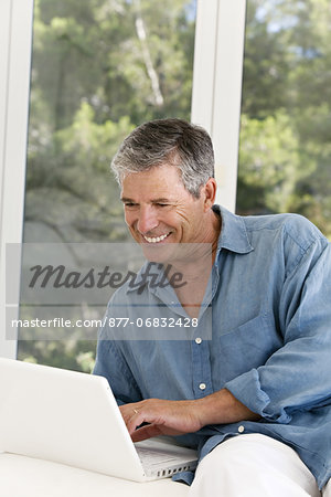 Senior man at home, using laptop