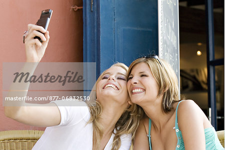 Two young women taking a self portrait with mobile, outside