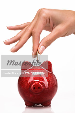 Woman's hand putting a coin in a piggy bank