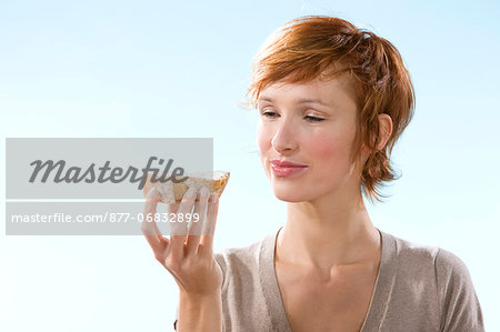 Portrait of woman holding a sandwich on light blue background