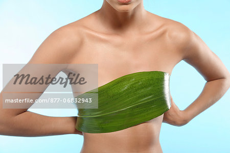 Young woman holding a aspidistra leaf on her chest