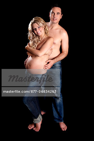 Man embracing topless pregnant woman