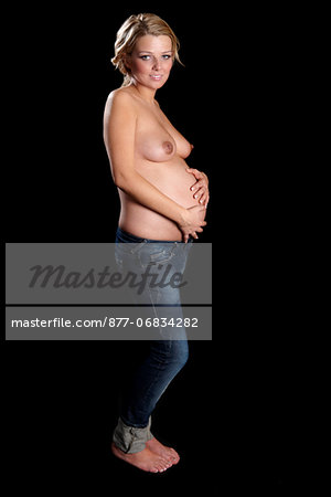 Topless pregnant woman with hands on stomach