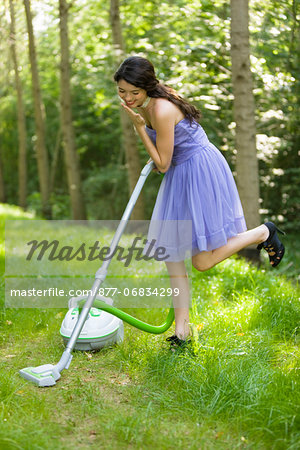 Young woman vacuuming grass