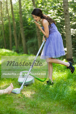 Young woman vacuuming grass