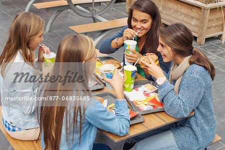 Teenager drinking some soft drink and eating an hamburger