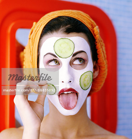 Portrait woman, towel on hair, face pack, putting cucumber slices on face