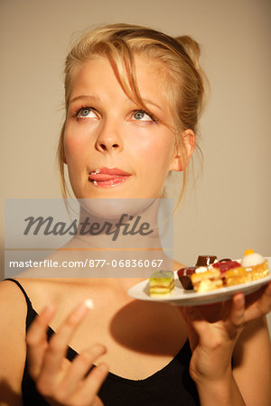Portrait of a young woman eating petits fours