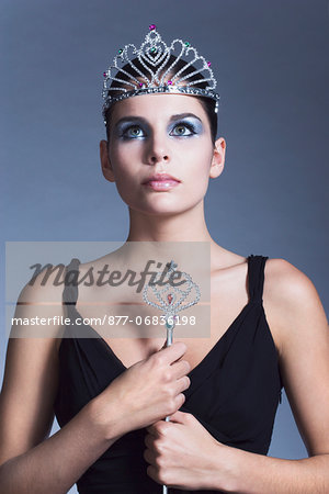 Young woman holding fairy wand, tiara, black dress