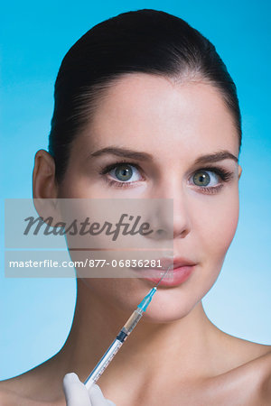 Young woman with syringe on lips