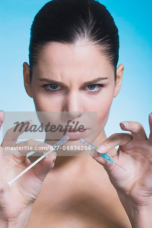 Young woman frowning, with broken syringe