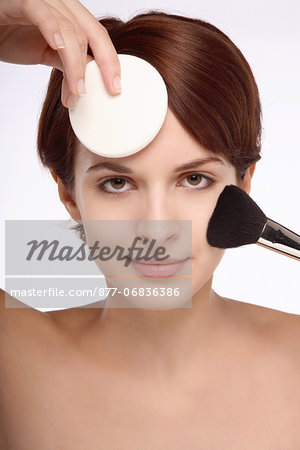 Portrait of a young brunette woman brush and sponge on face