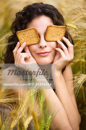 Young woman covering eyes with rusks