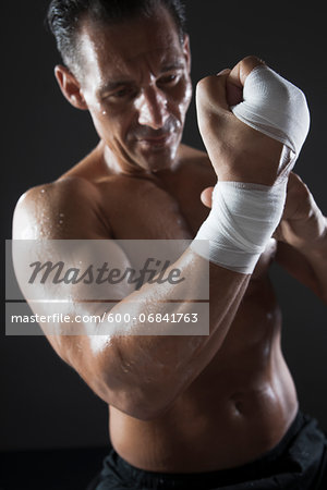 Muscular Man Wrapping Hand with Sports Tape, Studio Shot