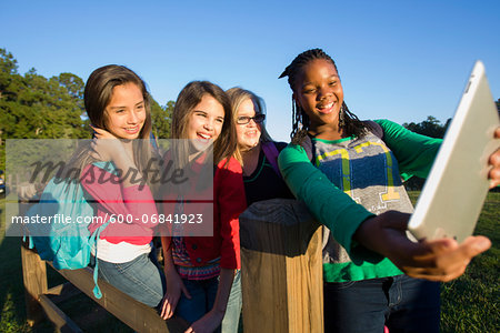 Pre-teen girls standing outdoors, looking at tablet computer laughing, Florida, USA