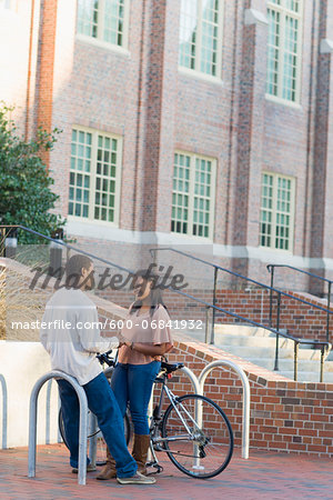 Young couple outdoors on college campus, talking next to bike rack, Florida, USA