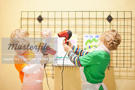 Boys playing with hair dryers whilst drying their paintings