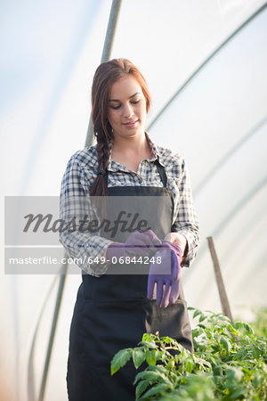 Young woman putting on gardening gloves