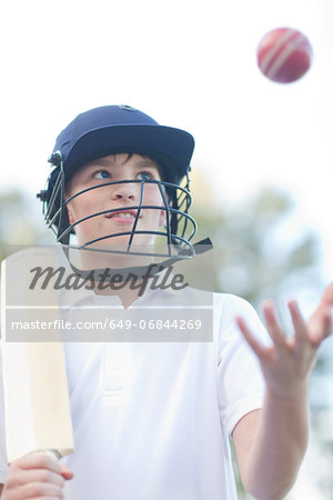 Boy wearing helmet catching cricket ball
