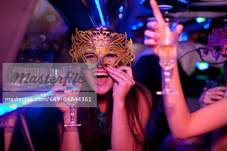 Young woman wearing mask with wine glass in limousine