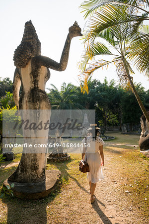Woman walking past statue, Xieng Khu, Vientiane, Laos