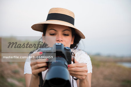 Woman wearing hat taking photograph