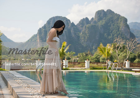 Woman dipping toe in swimming pool, Vang Vieng, Laos