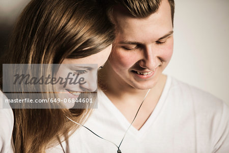 Teenage couple smiling and sharing earphones