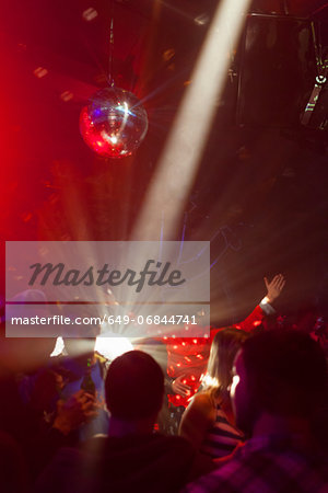 Nightclub scene with people dancing, disco ball, lighting equipment