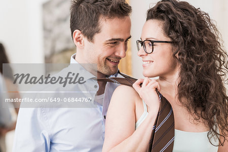 Mid adult woman pulling man's tie