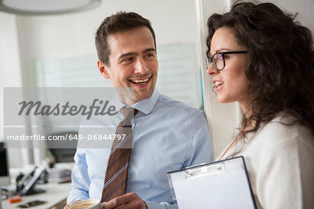 Mature man smiling at woman holding clipboard