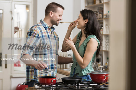Mid adult couple cooking dinner, tasting