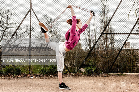 Woman in hoodie pulling pilates rope from behind bent leg