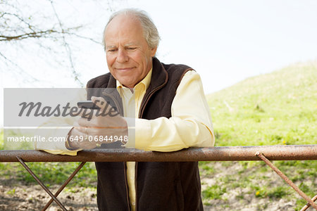 Senior man smiling at message on mobile phone